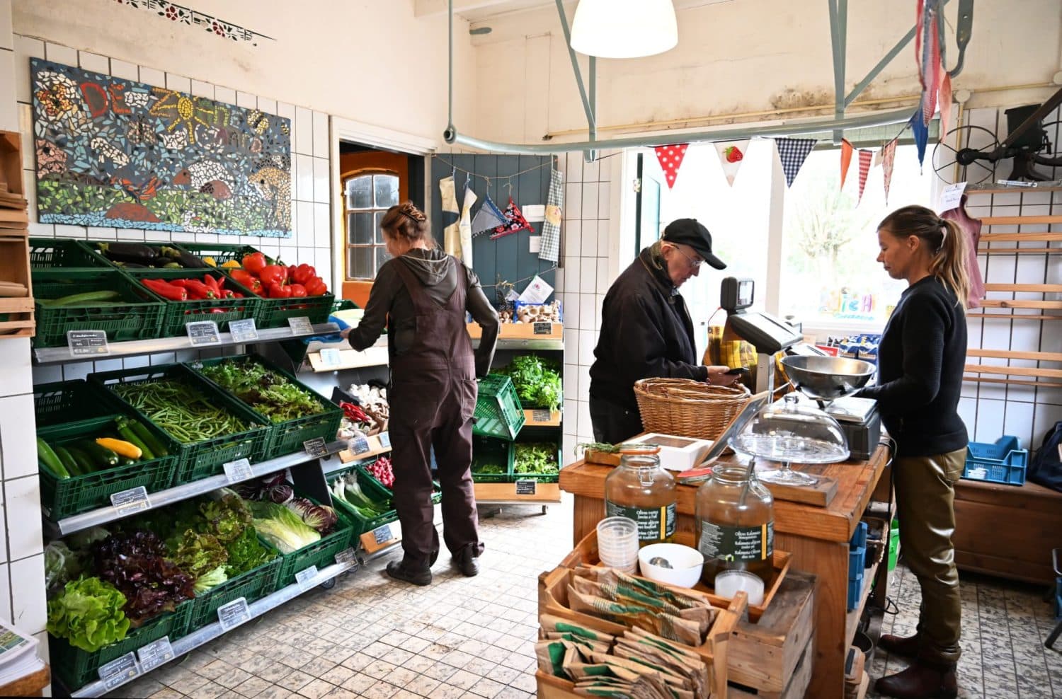 Momentopname van de bedrijvigheid in de boerderijwinkel van biologisch- dynamisch landbouwbedrijf De Zonnegaard in Voorst. Boodschappen worden afgerekend en er wordt bijgevuld.