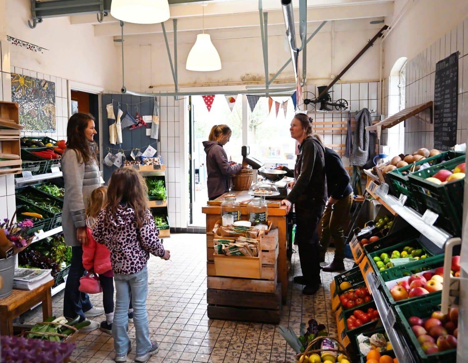 Een klant (moeder met twee jonge kinderen) stelt vragen over de biologisch- dynamische producten in de boerderijwinkel van De Zonnegaard.