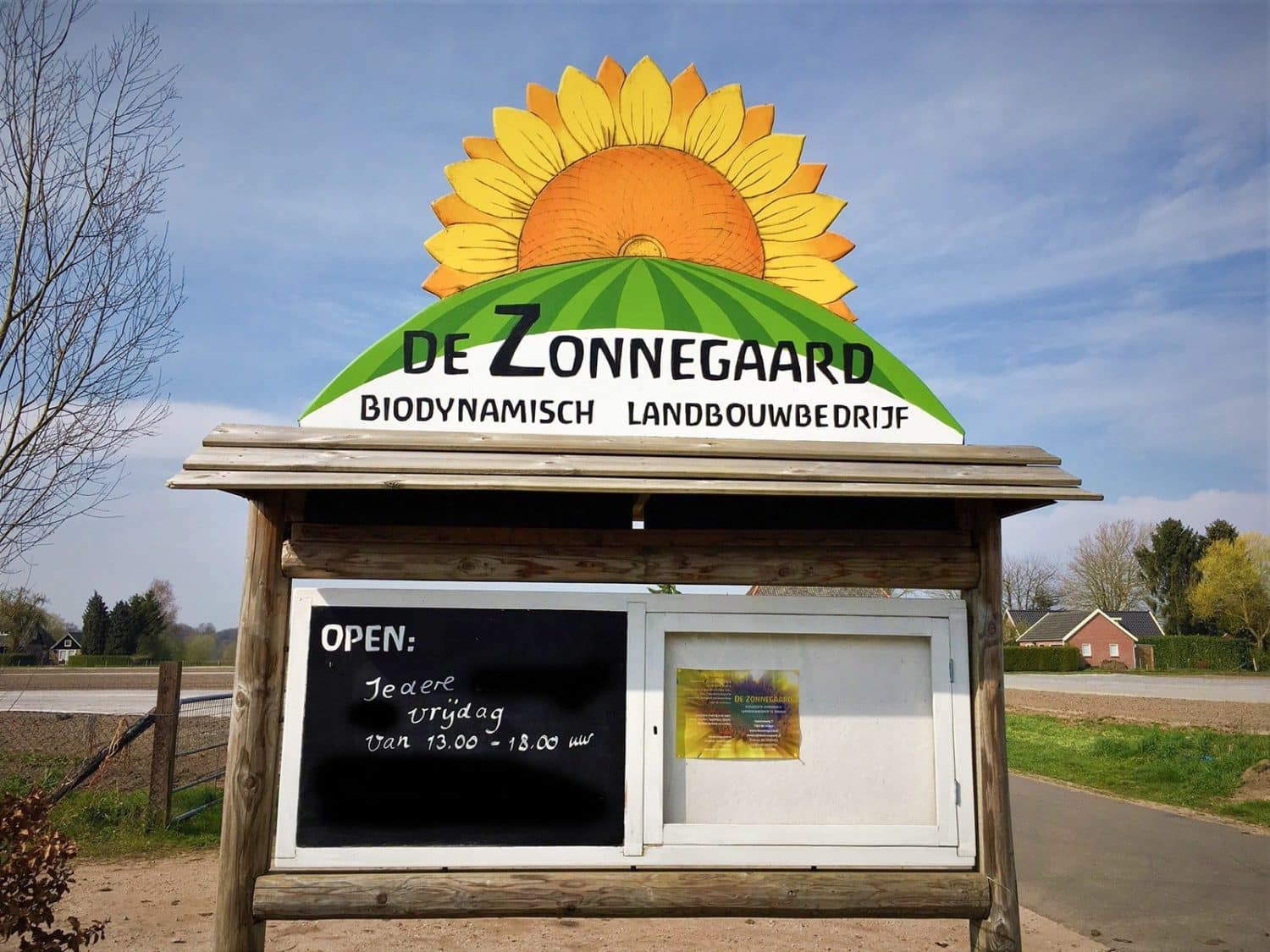 Het bord aan de Appenseweg met de openingstijden boerderijwinkel van biologisch- dynamisch landbouwbedrijf De Zonnegaard in Voorst en een prachtige versie van het logo.